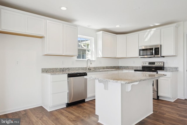 kitchen featuring white cabinetry, appliances with stainless steel finishes, dark wood-type flooring, and a center island