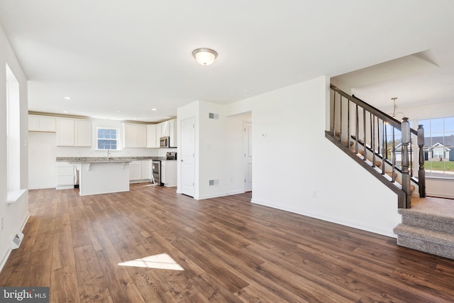 unfurnished living room featuring dark hardwood / wood-style floors, an inviting chandelier, and sink