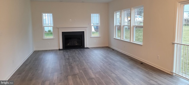 unfurnished living room with dark wood-type flooring and a wealth of natural light