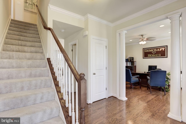 staircase featuring wood-type flooring, decorative columns, ceiling fan, and ornamental molding