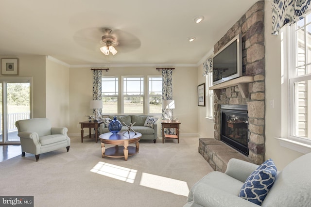 carpeted living room with a stone fireplace, ornamental molding, and a wealth of natural light