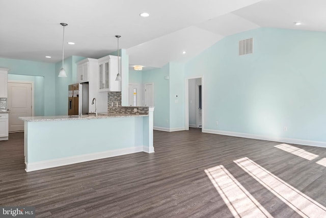 kitchen with lofted ceiling, white cabinets, decorative backsplash, light stone countertops, and decorative light fixtures