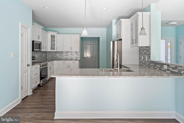 kitchen with white cabinetry, kitchen peninsula, stainless steel appliances, and hanging light fixtures