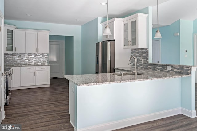 kitchen with kitchen peninsula, appliances with stainless steel finishes, sink, white cabinetry, and hanging light fixtures