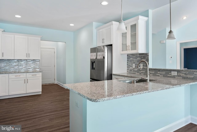 kitchen with kitchen peninsula, stainless steel fridge, white cabinets, and hanging light fixtures