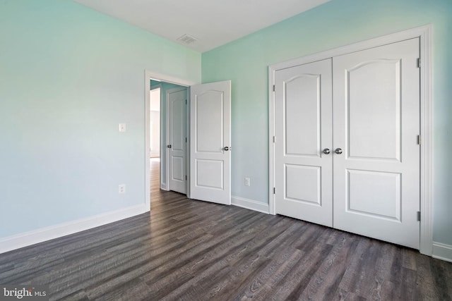 unfurnished bedroom with a closet and dark hardwood / wood-style floors