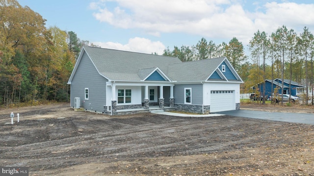 craftsman house with a porch, a garage, and central air condition unit