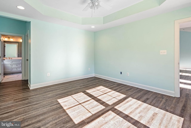 unfurnished room featuring ceiling fan, a raised ceiling, and dark wood-type flooring