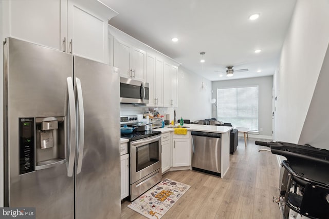 kitchen featuring stainless steel appliances, ceiling fan, kitchen peninsula, white cabinetry, and light wood-type flooring