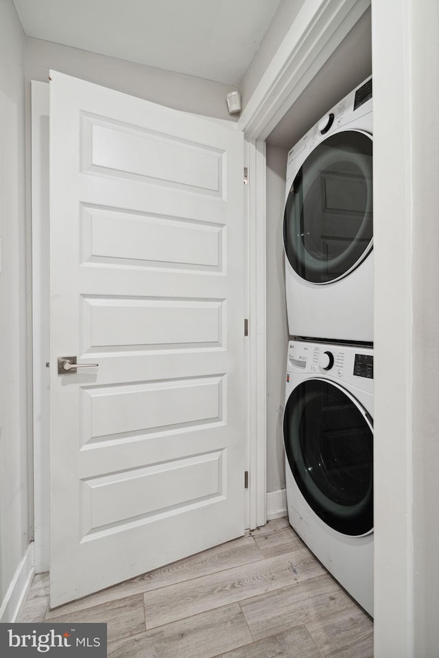 laundry area featuring light wood-type flooring and stacked washer / dryer