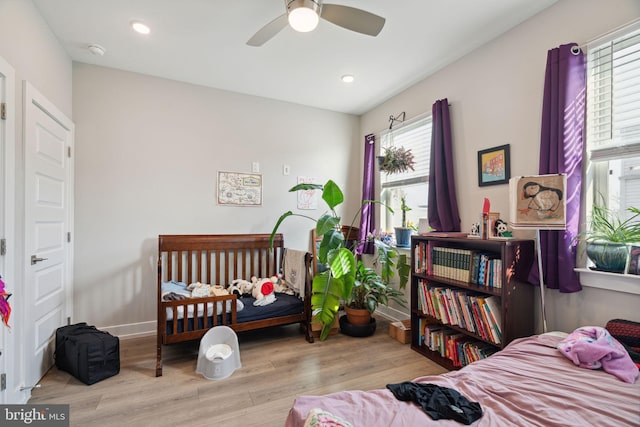 bedroom with ceiling fan, light hardwood / wood-style floors, and multiple windows