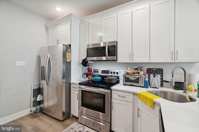 kitchen featuring light hardwood / wood-style floors, appliances with stainless steel finishes, white cabinetry, backsplash, and sink