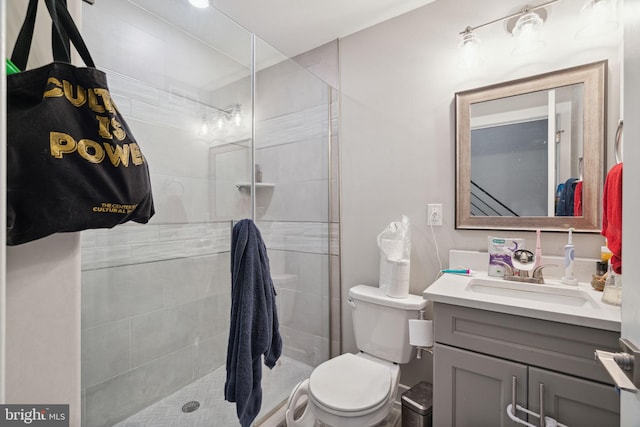 bathroom with an enclosed shower, vanity with extensive cabinet space, and toilet