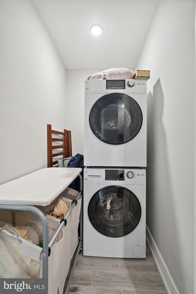 laundry area with stacked washing maching and dryer and light hardwood / wood-style floors