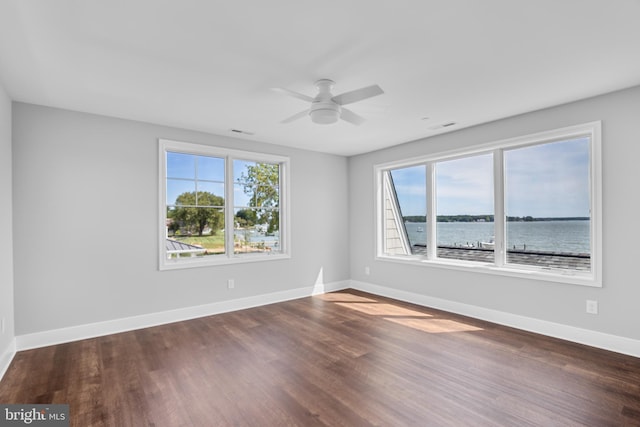 unfurnished room featuring ceiling fan, wood-type flooring, and a water view