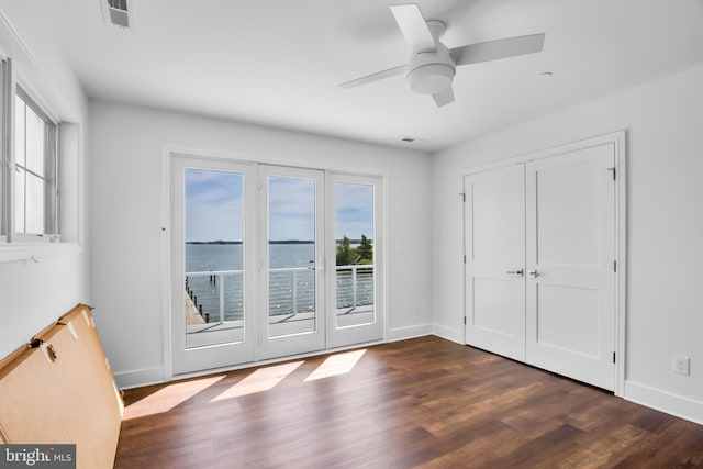 doorway featuring dark wood-type flooring, a water view, and ceiling fan