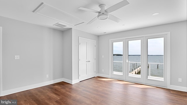 spare room featuring ceiling fan, dark hardwood / wood-style floors, and a water view