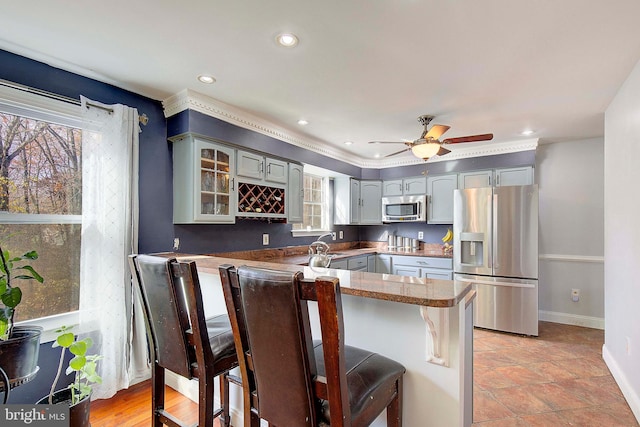 kitchen featuring a kitchen breakfast bar, plenty of natural light, ceiling fan, and stainless steel appliances