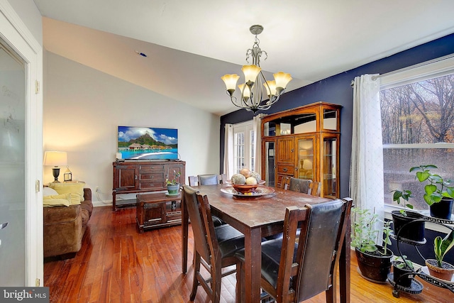 dining room featuring an inviting chandelier, lofted ceiling, and dark hardwood / wood-style flooring