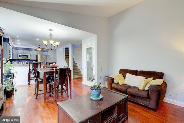 living room featuring dark hardwood / wood-style flooring, lofted ceiling, and ceiling fan with notable chandelier