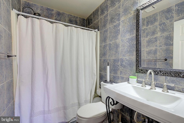 bathroom with sink, toilet, and tile walls