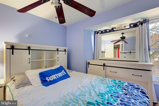 bedroom with a barn door and ceiling fan