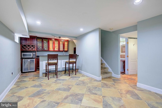 kitchen with a kitchen breakfast bar, light tile floors, and wine cooler