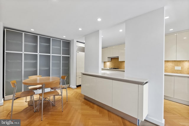 kitchen with built in fridge, stainless steel gas stovetop, light parquet flooring, tasteful backsplash, and white cabinetry