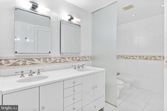 bathroom with tile flooring, tile walls, a bidet, toilet, and double sink vanity