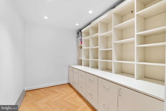 walk in closet with light parquet floors