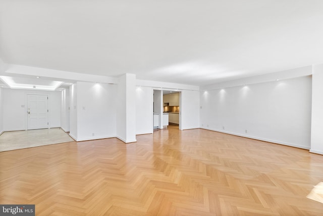 interior space with light parquet floors and a tray ceiling