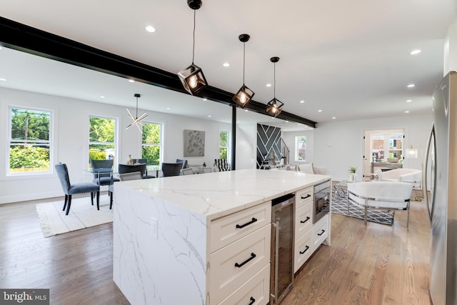 kitchen featuring wine cooler, freestanding refrigerator, open floor plan, white cabinets, and a kitchen island