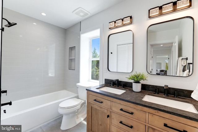 full bath featuring toilet, double vanity, a sink, and tile patterned floors