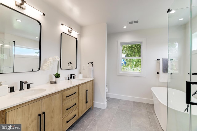 full bathroom with plenty of natural light, visible vents, a sink, and a freestanding bath