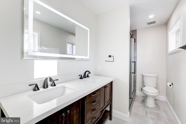 full bathroom with toilet, a shower stall, double vanity, and a sink