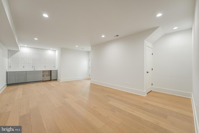 unfurnished living room featuring light wood-type flooring, visible vents, a sink, and recessed lighting