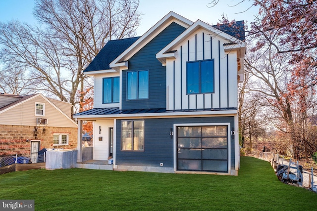 rear view of property with roof with shingles, a yard, board and batten siding, a standing seam roof, and metal roof