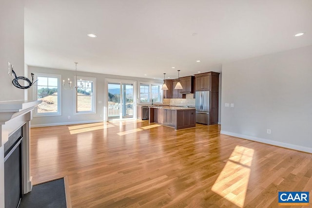 unfurnished living room featuring a notable chandelier, light hardwood / wood-style flooring, and sink