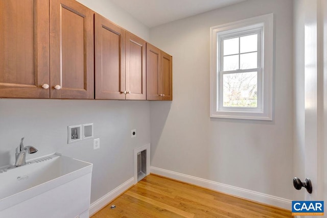 laundry area with sink, hookup for a washing machine, electric dryer hookup, light hardwood / wood-style flooring, and cabinets