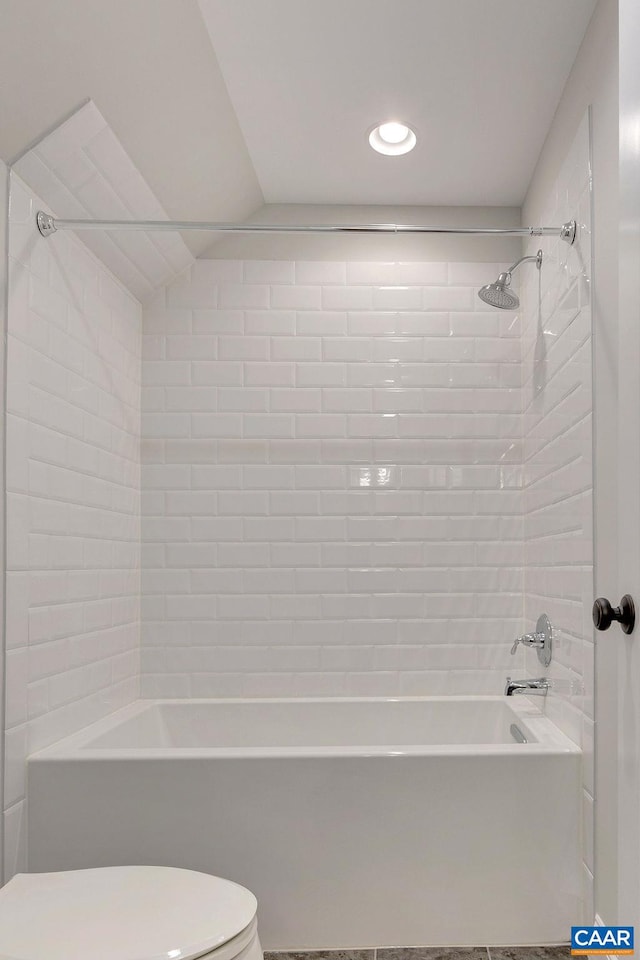 bathroom featuring tile floors, toilet, and tiled shower / bath