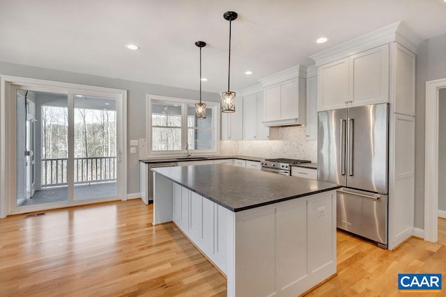 kitchen with a kitchen island, light hardwood / wood-style floors, high end appliances, and white cabinetry