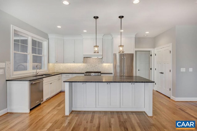 kitchen featuring decorative light fixtures, white cabinetry, appliances with stainless steel finishes, light hardwood / wood-style flooring, and a center island