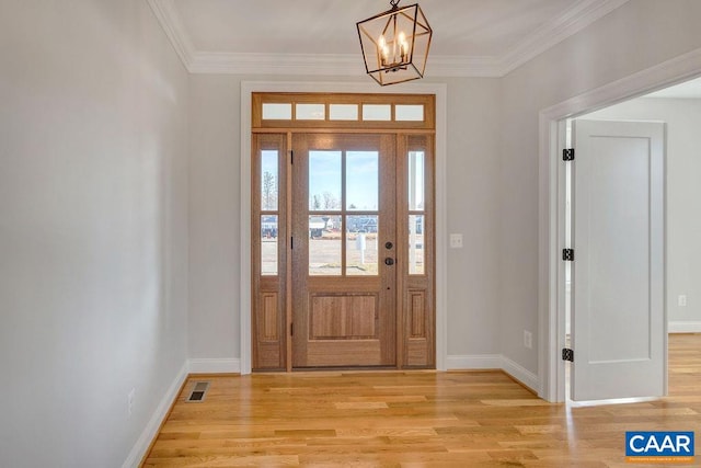 entrance foyer with an inviting chandelier, ornamental molding, and light hardwood / wood-style flooring