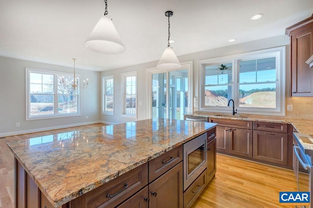 kitchen with pendant lighting, tasteful backsplash, a kitchen island, stainless steel appliances, and light hardwood / wood-style floors