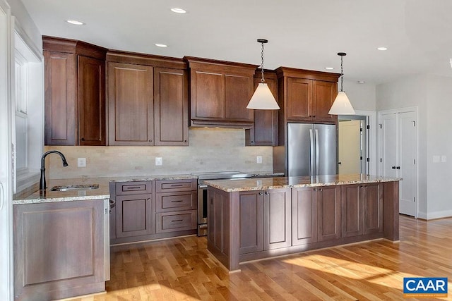 kitchen featuring light hardwood / wood-style flooring, stainless steel refrigerator, range, and decorative light fixtures