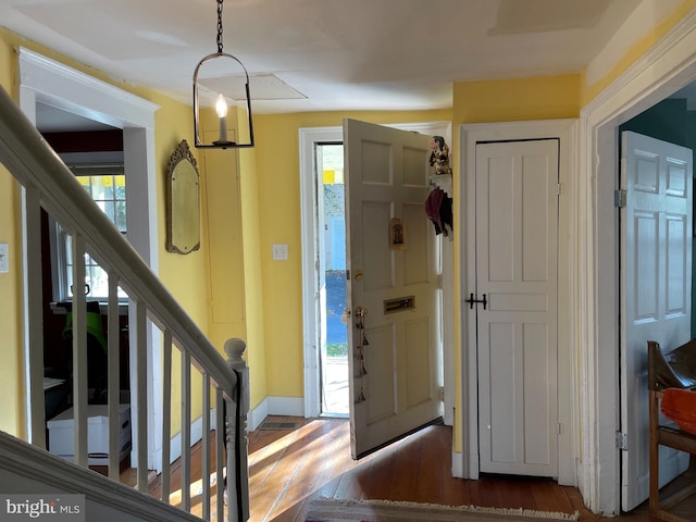 entryway featuring dark wood-type flooring and an inviting chandelier