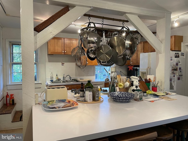 kitchen featuring white fridge with ice dispenser, a kitchen breakfast bar, and sink