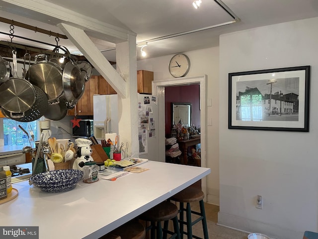 kitchen featuring tile floors, white fridge, and a breakfast bar area