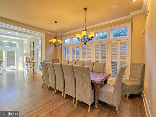 dining space with ornamental molding, wood-type flooring, and a chandelier