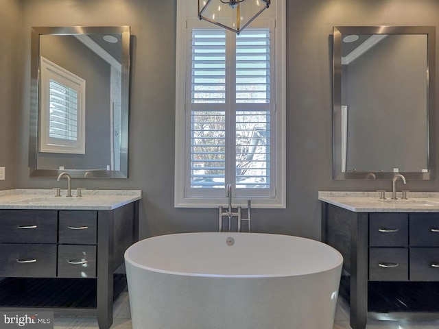 bathroom featuring ornamental molding, double sink, a bathing tub, and large vanity